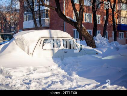 A passenger car in winter was covered with snow after a snow storm. Stock Photo