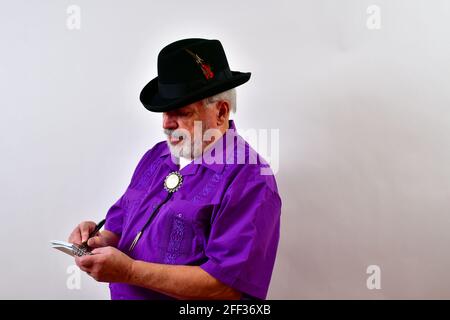 View of an elderly man wearing a purple shirt and taking notes on a white backgrounjd Stock Photo