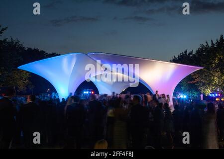 Crowds of people gathering outside Lilas, for the Serpentine summer party. Lilas Pavilion - Serpentine Gallery, London, United Kingdom. Architect: Zah Stock Photo