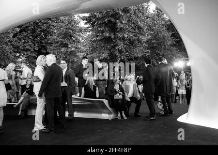 Crowds of people gathering outside Lilas, for the Serpentine summer party. Lilas Pavilion - Serpentine Gallery, London, United Kingdom. Architect: Zah Stock Photo