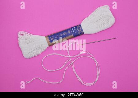 Sashiko Japanese embroidery needle and thread on a pink background. Stock Photo