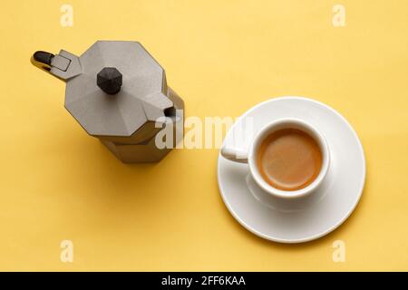 Traditional Italian coffee pot for espresso and coffee in a cup on yellow background Stock Photo