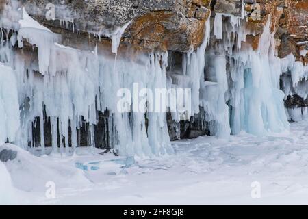 The rock on the frozen lake Baikal is covered with a thick layer of blue ice: many icicles and splashes Stock Photo