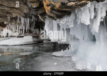 The rock on the frozen lake Baikal is covered with a thick layer of blue ice: many icicles and splashes Stock Photo