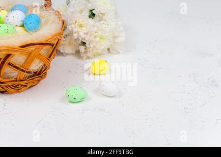 Easter eggs painted in pastel colors on a white table against the background of a basket of Easter eggs. Selective focus. Place for an inscription Stock Photo
