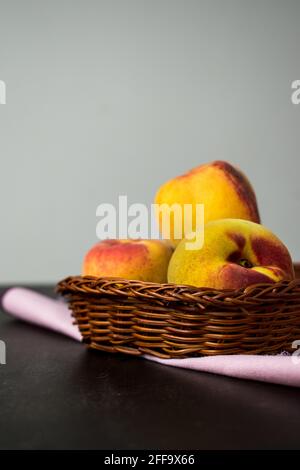 basket of peaches on a black wooden table with a white background Stock Photo