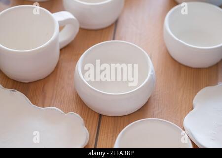 Handicraft production of white clay cups. Handmade ceramics before firing standing on table Stock Photo
