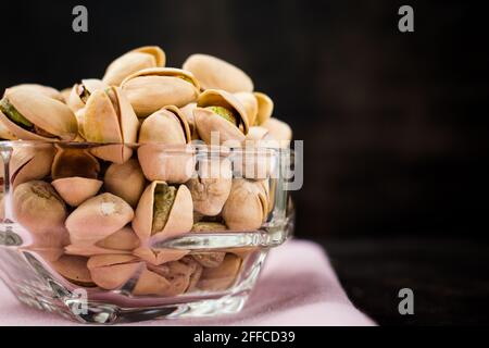 Some pistachios in a glass bowl on a black wooden table Stock Photo