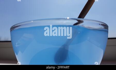 The brush is rinsed from blue paint in transparent glass. Stock Photo