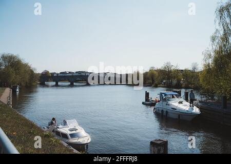 Staines-upon-Thames, Spelthorne  | UK -  2021.04.24: Boats moored at the Chertsey Lock on the Thames river next to the bridge Stock Photo