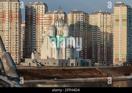 An unusual Orthodox church under construction stands against a background of high-rise apartment buildings. Stock Photo