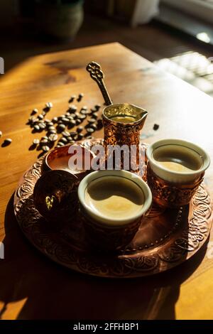 Turkish coffee served in copper cup and pot.Coffee beans on brown wooden table. Stock Photo