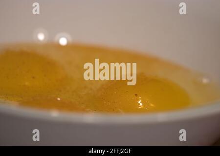 eggs cracked into a simple white bowl with some salt Stock Photo