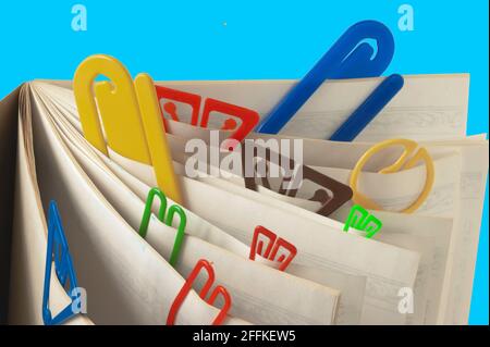 Close up isolated image of 10 paperclips separating pages in a book or tablet. Paper clips represent many sizes and colors and show differences. Stock Photo