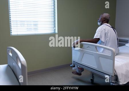 Portrait of african american male patient sitting on hospital bed looking through the window Stock Photo