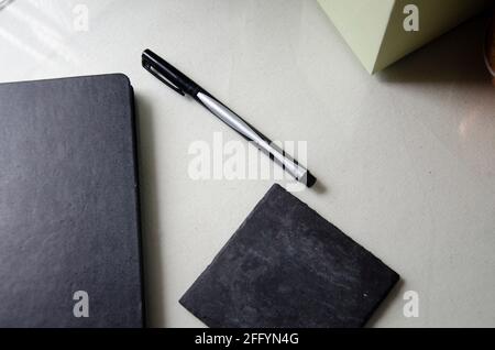 Glass Desk with Black Notepad, Pen, & Coaster Set Up Stock Photo
