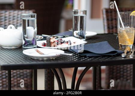 Leftover food waste concept image featuring an outdoor cafe table with no customer but leftover cakes and drinks which will be trashed. Inconsiderate Stock Photo