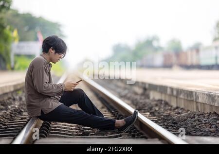 Depressed Young Man Sitting On Railway Track