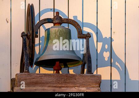 Closeup isolated image of a rusty church bell immobilized on wooden blocks through metal framing. There is an ancient wheel mechanism to operate it sy Stock Photo