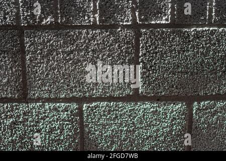 Sunlight shines just past a brick wall, creating a textured effect. Stock Photo