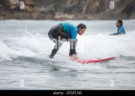 Galicia, Spain - August 2, 2020: Surf lessons on the beach of San Antonio, Espasante. Novice surfers, learning with their surfboards on a cloudy day, Stock Photo