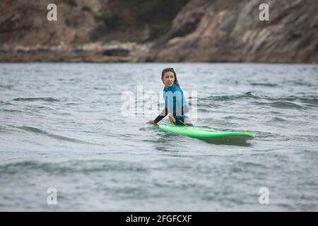 Galicia, Spain - August 2, 2020: Surf lessons on the beach of San Antonio, Espasante. Novice surfers, learning with their surfboards on a cloudy day, Stock Photo