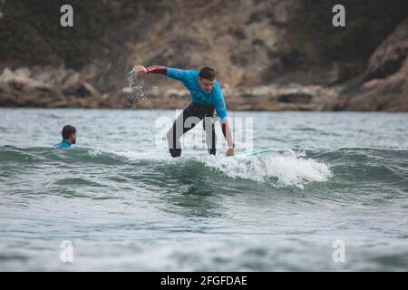 Galicia, Spain - August 2, 2020: Surf lessons on the beach of San Antonio, Espasante. Novice surfers, learning with their surfboards on a cloudy day, Stock Photo