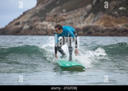 Galicia, Spain - August 2, 2020: Surf lessons on the beach of San Antonio, Espasante. Novice surfers, learning with their surfboards on a cloudy day, Stock Photo