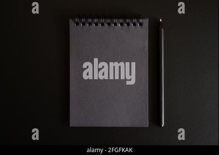 notebook on a spring with black sheets and a pen on a black background. space for text Stock Photo
