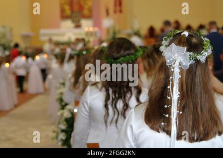 Celebration of Fistt Holy Communion in Catholic church, Poland, girls in white dresses, wreath, inside church during holy mass Stock Photo