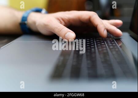 male hand typing on the keyboard a laptop. working man programmer. work from home. workplace with a laptop. selective focus Stock Photo