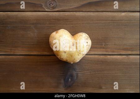ugly food. an ugly vegetable a heart shaped potato on a wooden plank table Stock Photo