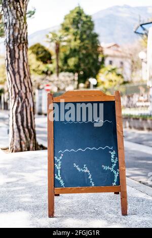 Premium Photo  Wooden easel stands on a stand against the backdrop of a  building and a beautiful green spruce