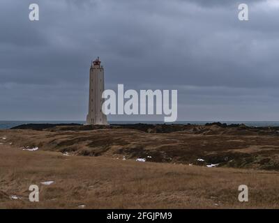 Beautiful view of Malarrif lighthouse (built 1946) on the western coast of Snæfellsnes peninsula, west Iceland on cloudy winter day with brown grass. Stock Photo
