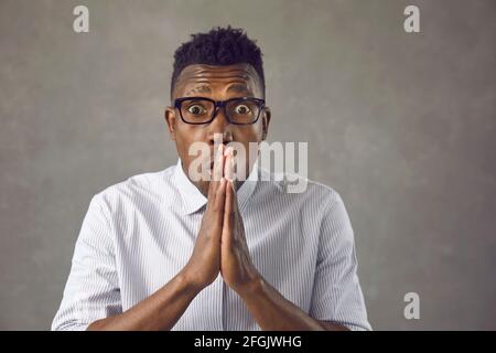 Studio portrait of shocked young African American man in glasses looking at camera Stock Photo