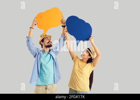 Two happy tourists holding conversation bubbles isolated on light gray background Stock Photo