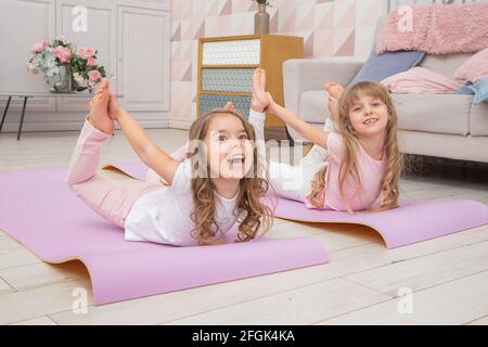 Full length front view smiling cute playful little preschool girls sitting  on on yoga mat do various exercises. Happy kids practicing yoga exercised a  Stock Photo - Alamy