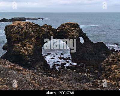 View of famous natural arch Gatklettur formed of volcanic basalt rocks on the rough Atlantic coast of Arnarstapi, Snæfellsnes peninsula, Iceland.