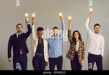 Creative business people holding glowing light bulbs standing on gray studio background Stock Photo