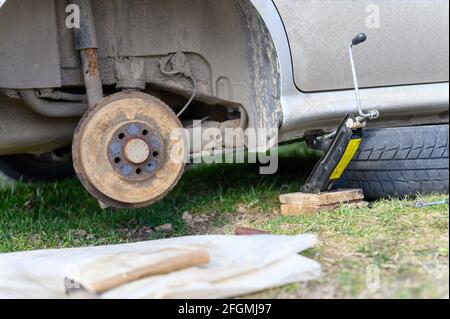 own repair of car drum brake himself. repair of broken car drum brake disassembled outdoor Stock Photo