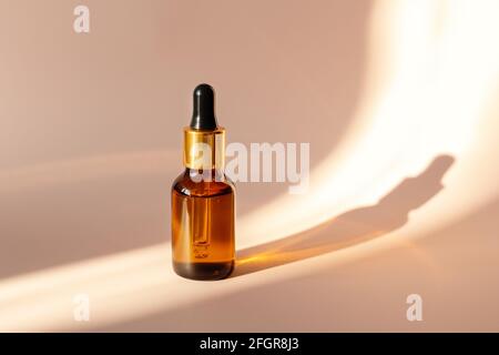 Glass bottle with essential oil or serum, hard light, deep shadows, copy space. Skin care concept - Image Stock Photo