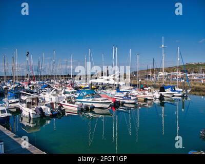 In sunshine on a calm sunny day, leisure boats moored on piers at Maryport Marina in north west Cumbria, England, UK. In the calm water are reflection Stock Photo