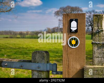 Fixed to a wooden post on a stile, a direction marker and white acorn logo of the Natural England National Trail, the Hadrian's Wall Path. Stock Photo