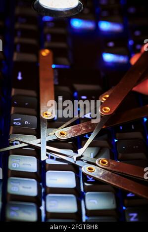 Dark environment with an illuminated keyboard and various break-in tools symbolizing cyber crime. Stock Photo