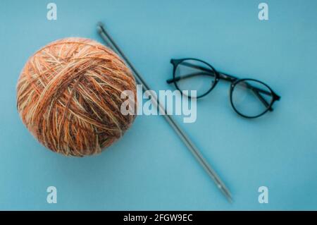 Ball of yarn, knitting needles and glasses. Flat lay Stock Photo