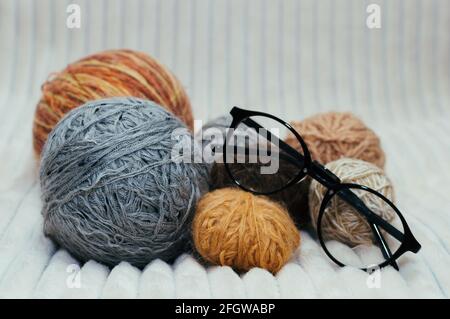 Balls of yarn with glasses for knitting lie on the bed. Close-up Stock Photo