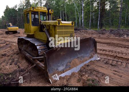 Dozer during clearing forest for construction new road . Yellow Bulldozer at forestry work Earth-moving equipment at road work, land clearing, grading Stock Photo