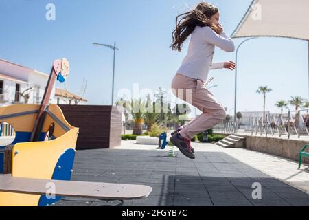 Child girl jumping from Walking the plank of playground pirate ship. Vitality and imagination concept for children Stock Photo