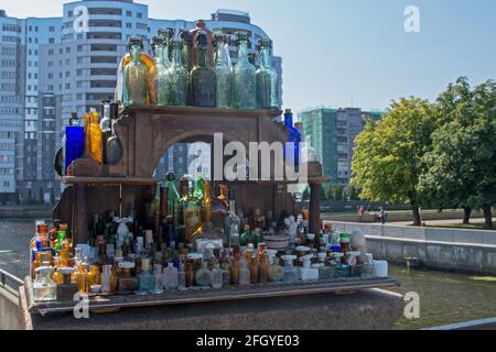 Collection of vintage clear vessels in shades of blue, green and brown on vintage wooden street vendor's rack near by Honey bridge over Pregolya river Stock Photo