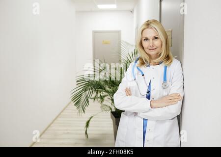 Portrait of an attractive general practitioner woman with arms crossed standing at a medical clinic Stock Photo